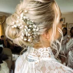beautiful wedding updo bun with flowers on blonde balayaged hair.