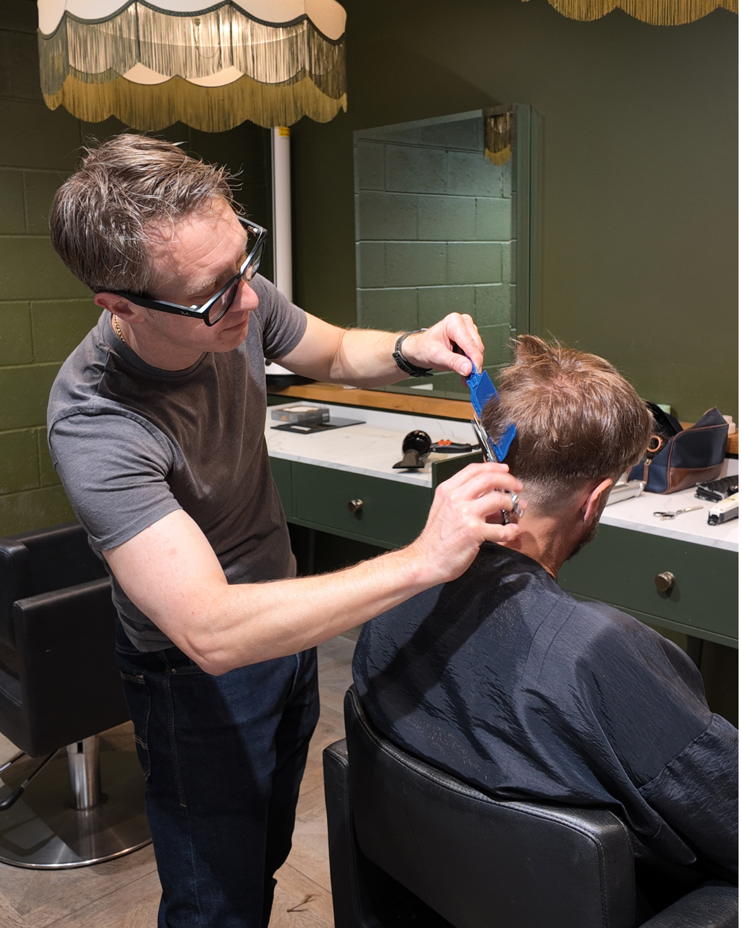Stylist cutting a short cropped hairstyle with scissors in a bright Manchester salon