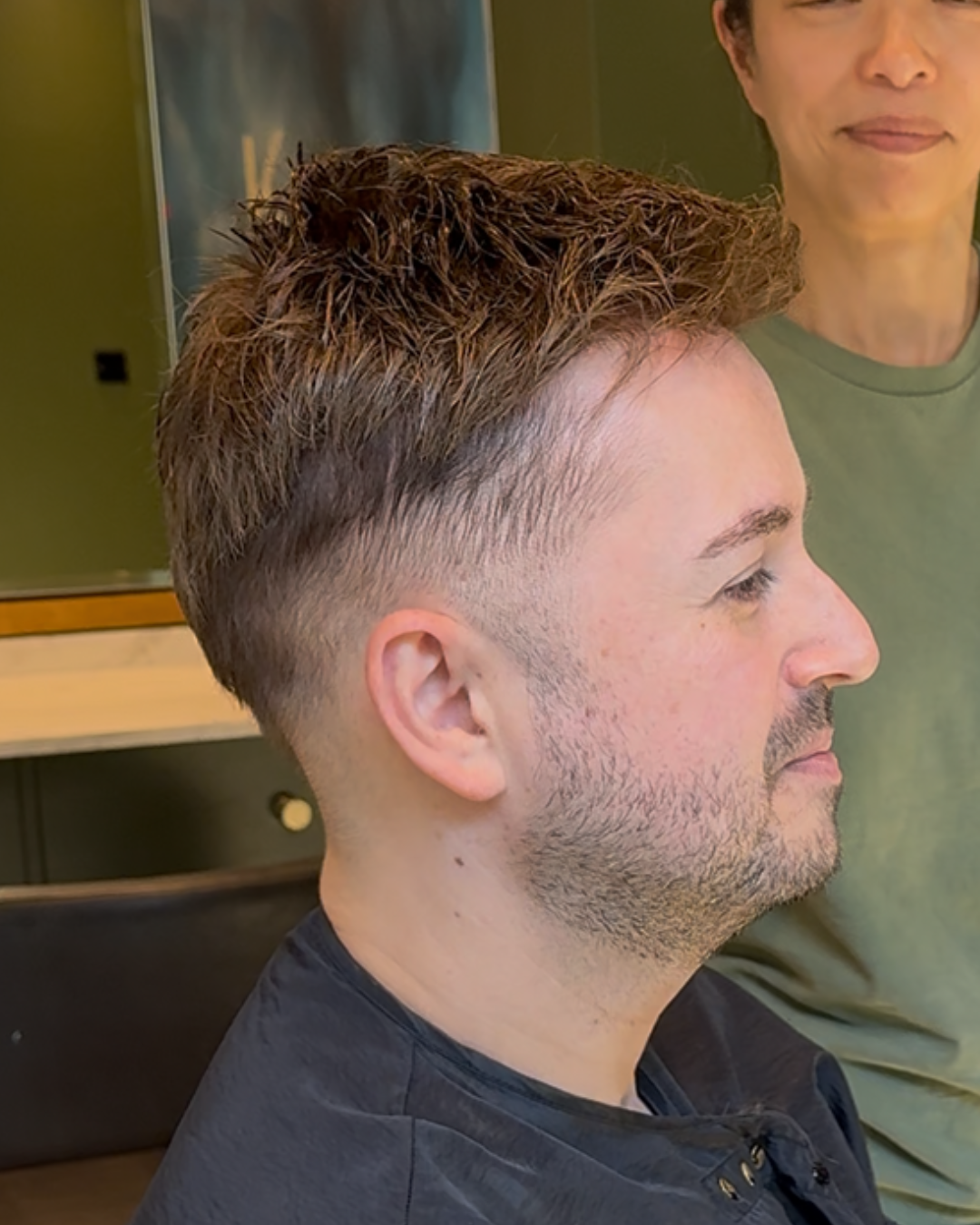 Side profile of a man in a salon with faded sides blended into his hair system