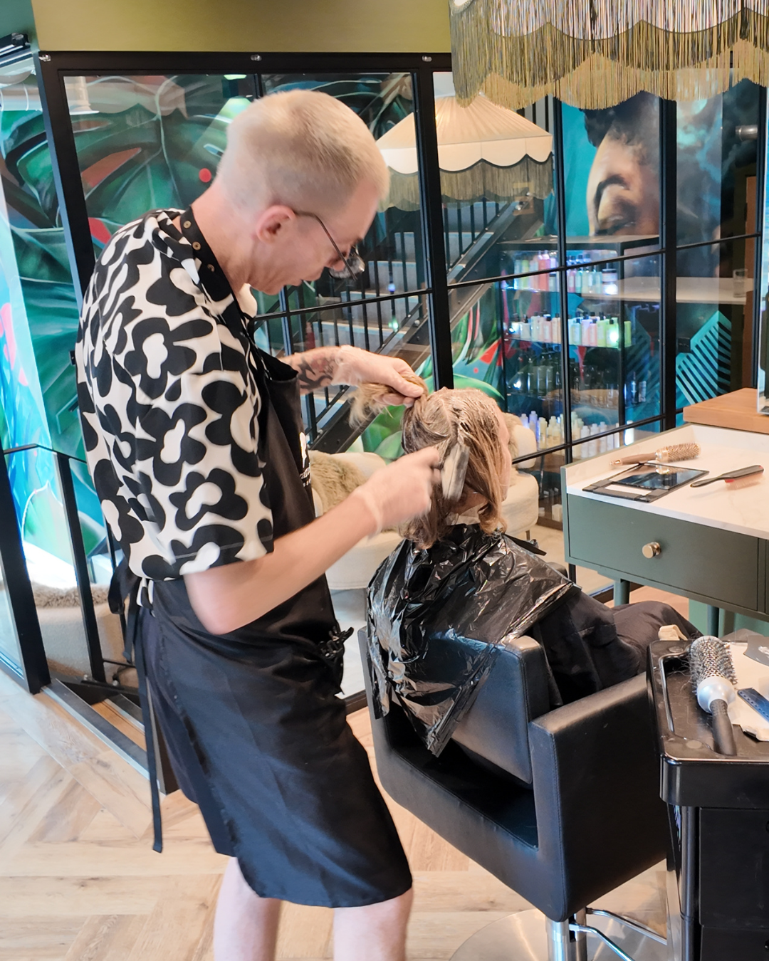 Hairdresser applying foils for highlights to a client's hair in a bright salon