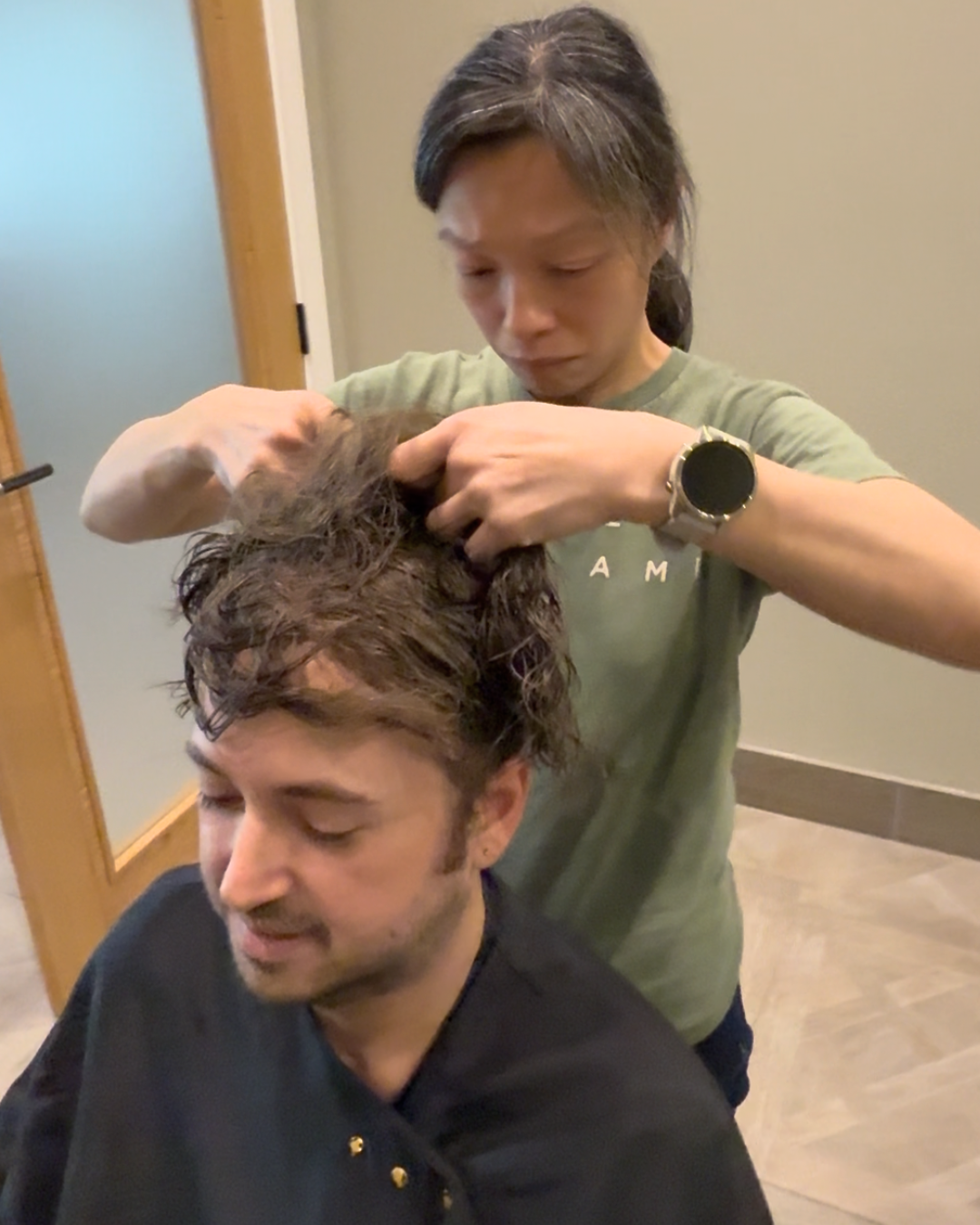 Stylist matching a hair system base to a client's natural hair colour in a salon