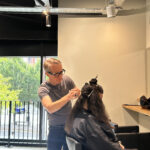 Stylist cutting and blow drying a client's freshly coloured hair