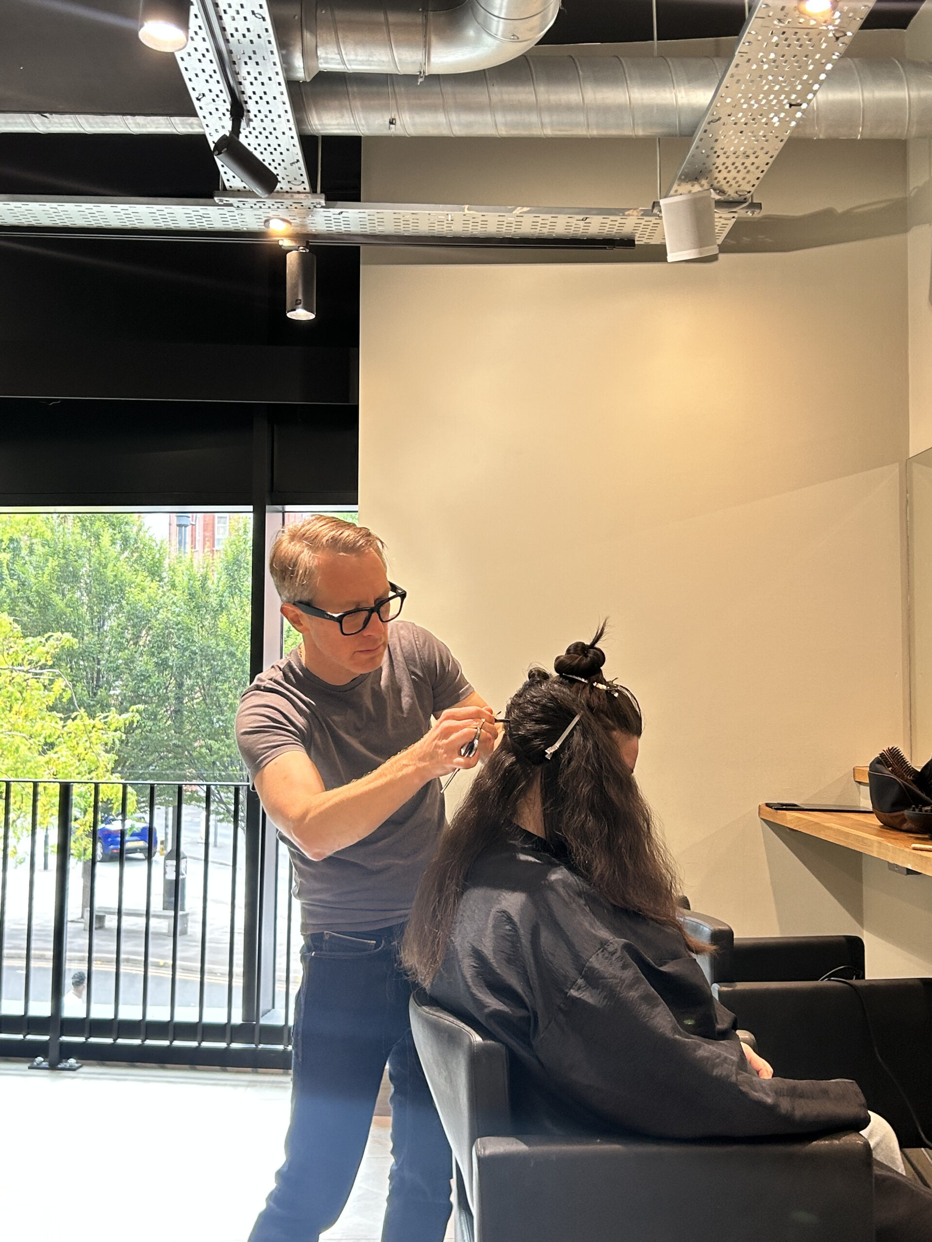 Stylist cutting and blow drying a client's freshly coloured hair