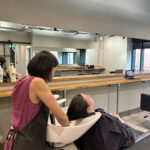 Stylist washing thick black hair at a wash basin in a salon chair